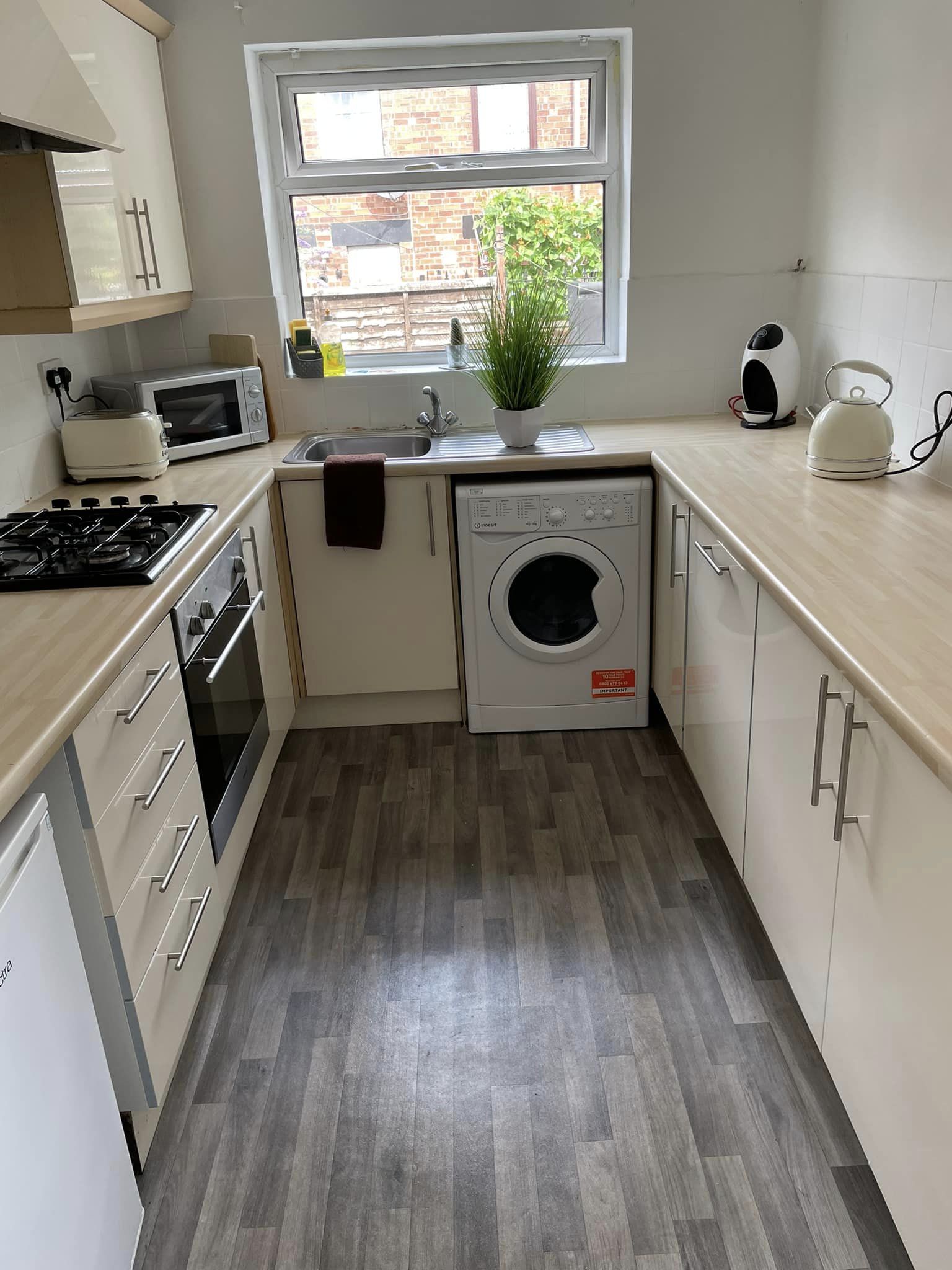 Small narrow kitchen with cream cupboards and worktops