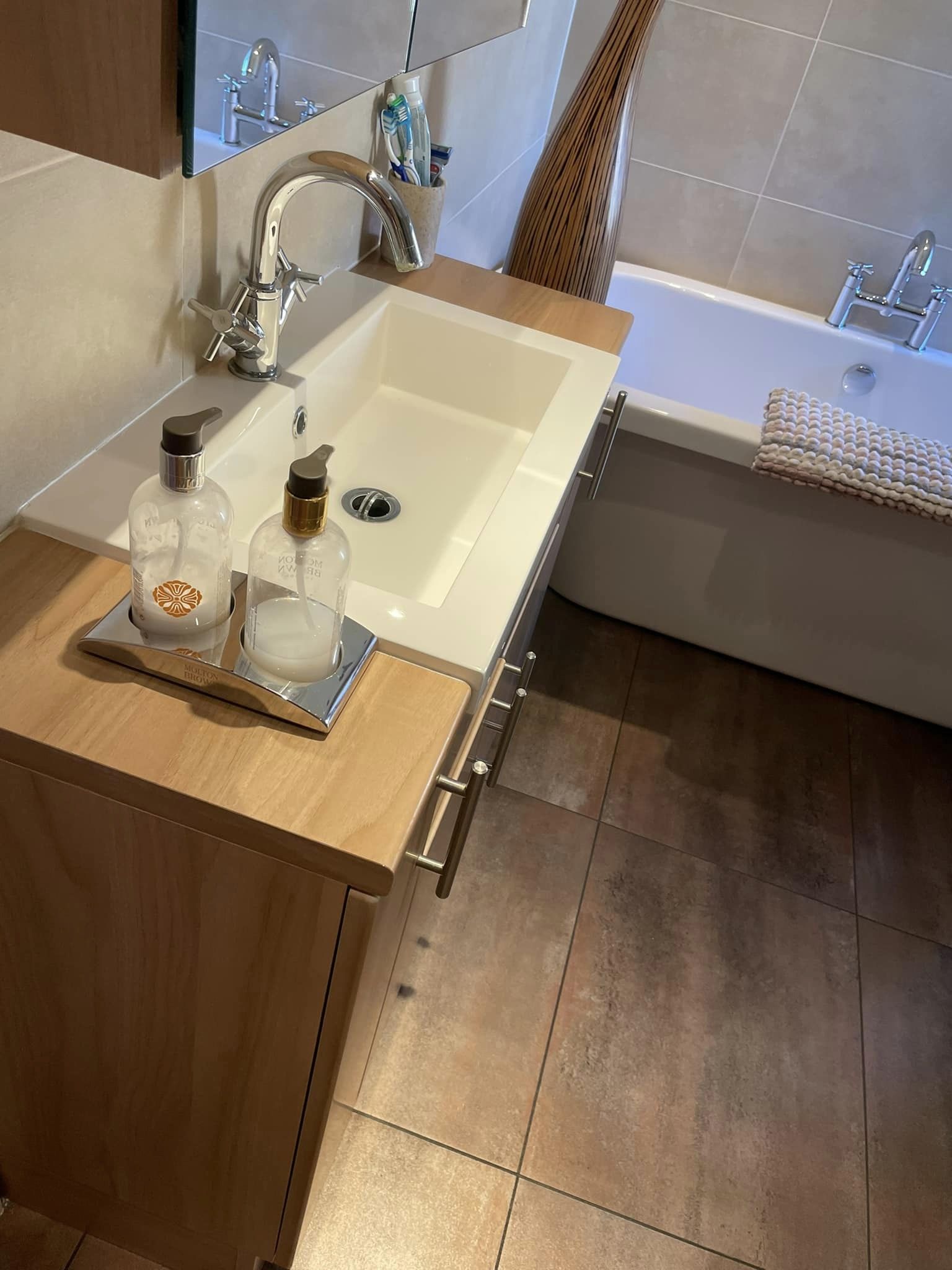 Small bathroom with curved bath and small sink